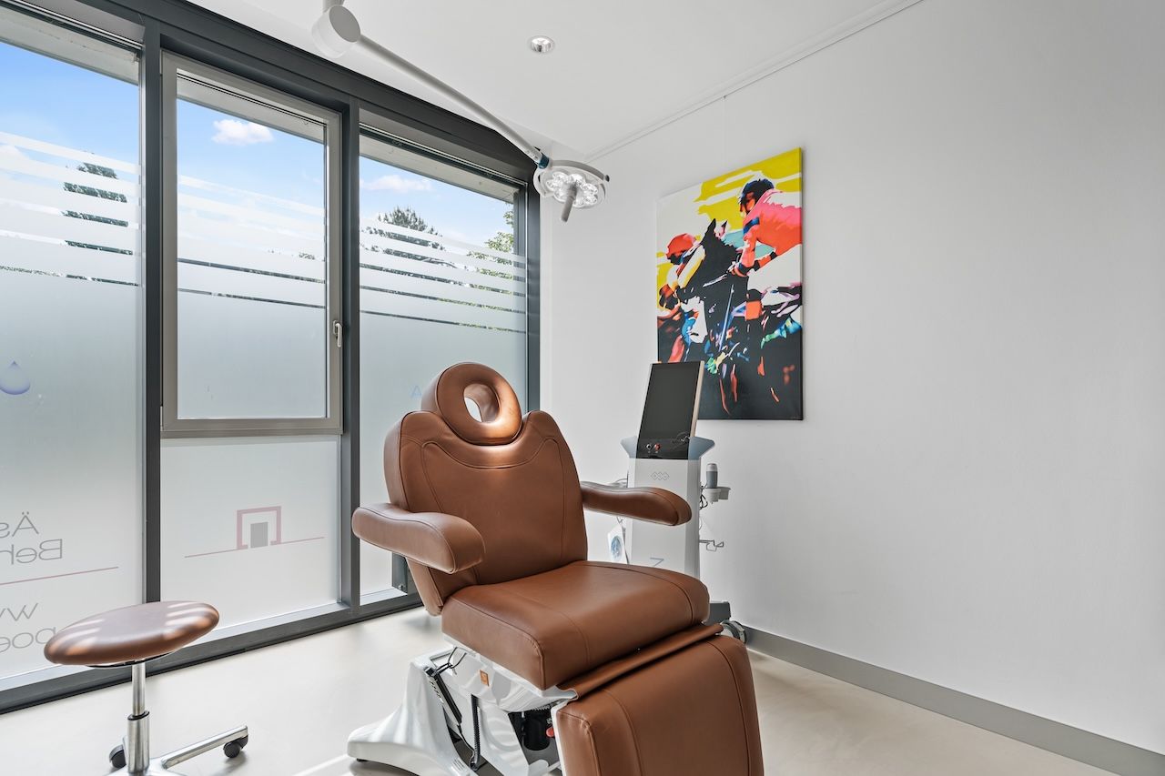 Behandlungsraum der Klinik mit Behandlungsstuhl, Behandlungsleuchte und fahrbarem Gerät